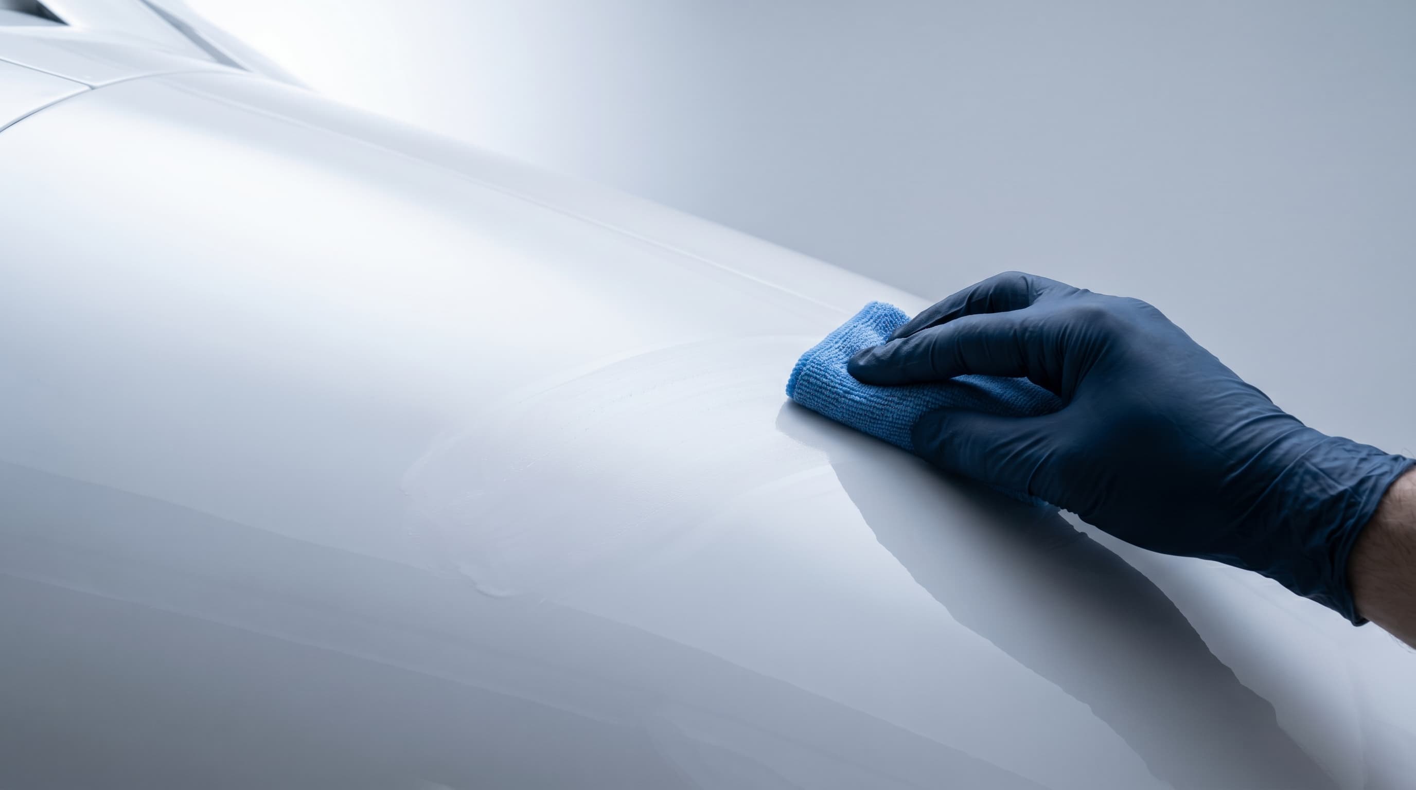 Detailer working a microfiber pad across a glossy white fuselage panel