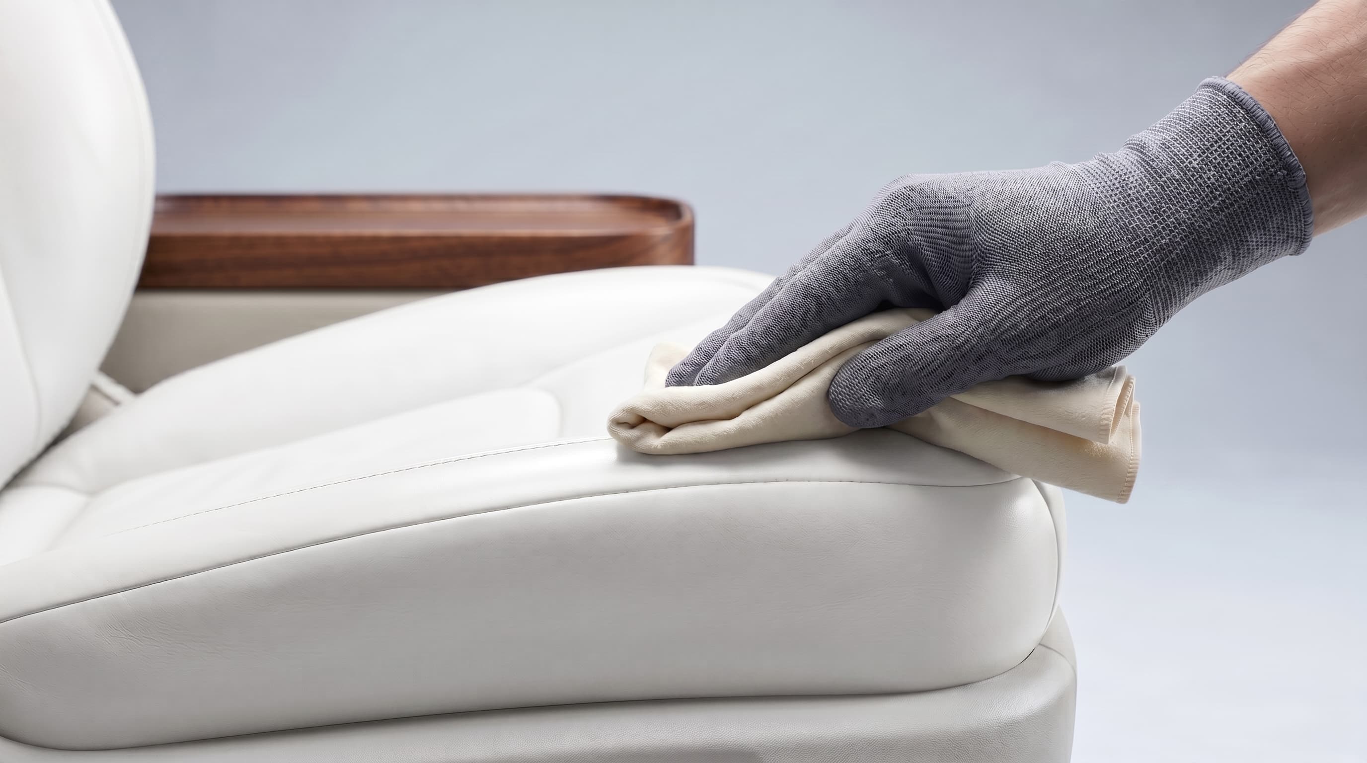 Conditioning cloth working into cream leather captain's chair stitching