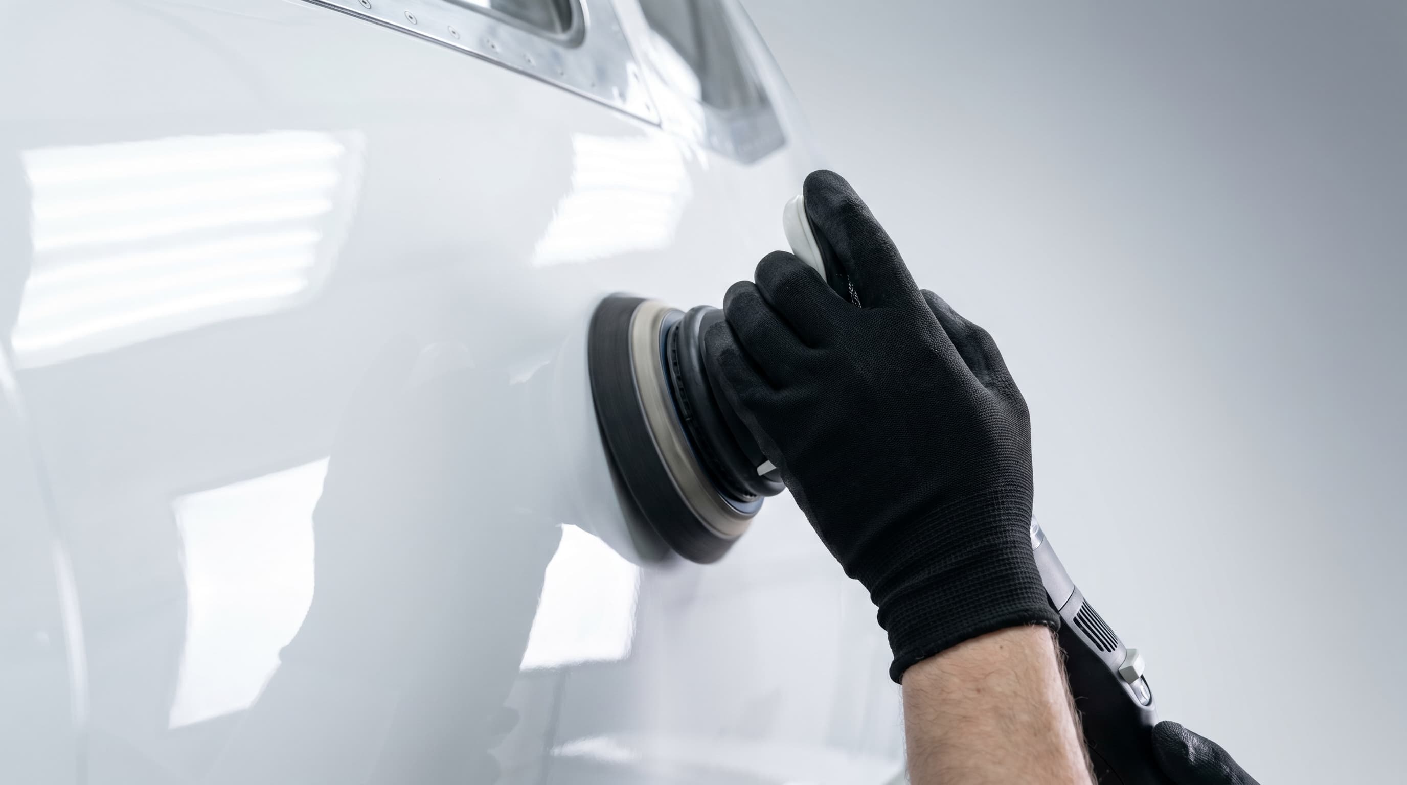 Machine polishing a white private jet side panel